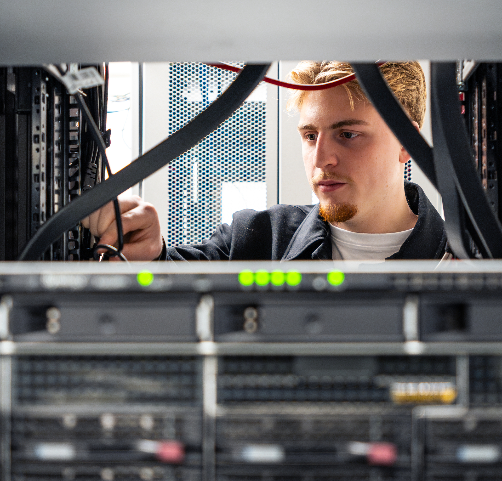 Mitarbeiter der LandService arbeitet im Serverraum, mit unscharfen Servern im Vordergrund